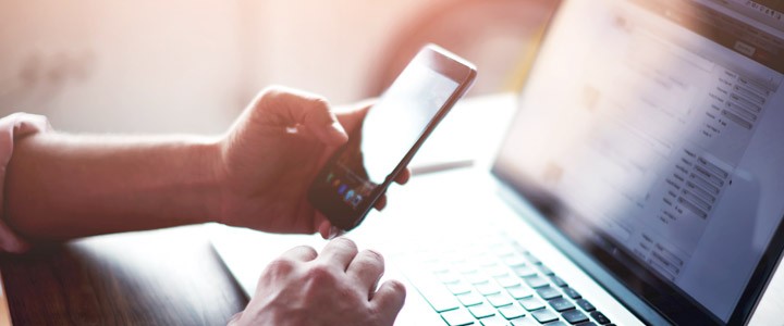 A person using the smartphone to dial a number that is in the notebook.